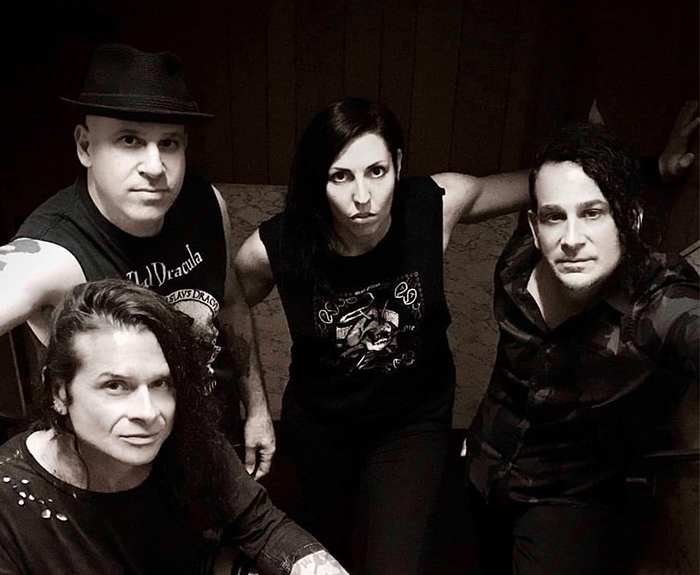 Rock singer with bandmates in a black and white photo, wearing casual outfits.