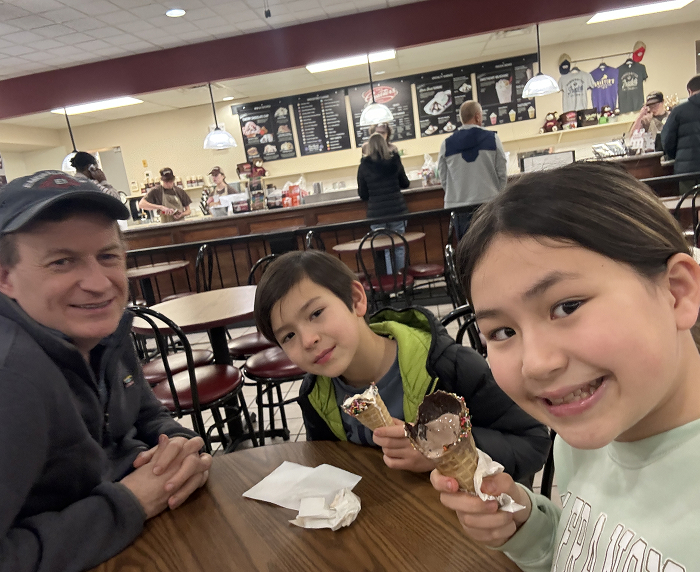 Dad and grown-up kids from viral interview sharing ice cream at a cafe.