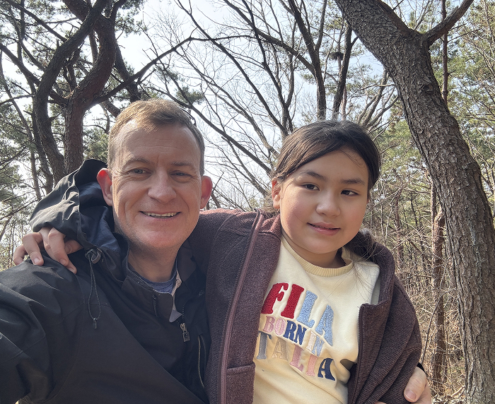 Man with child outdoors, both smiling, sparking nostalgia related to the viral "BBC Dad" interview moment.