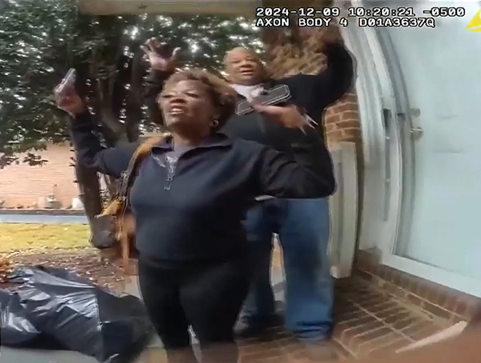 Loletha Hale stands with raised hands at the doorway, reclaiming her home from a squatter.