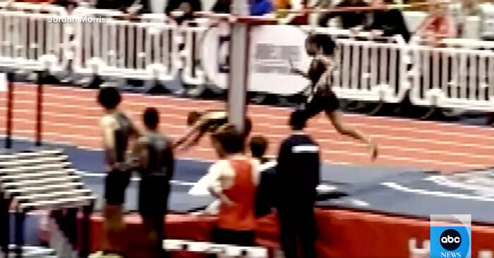 Athlete in mid-run during a track event, highlighting a controversial incident with an opponent.