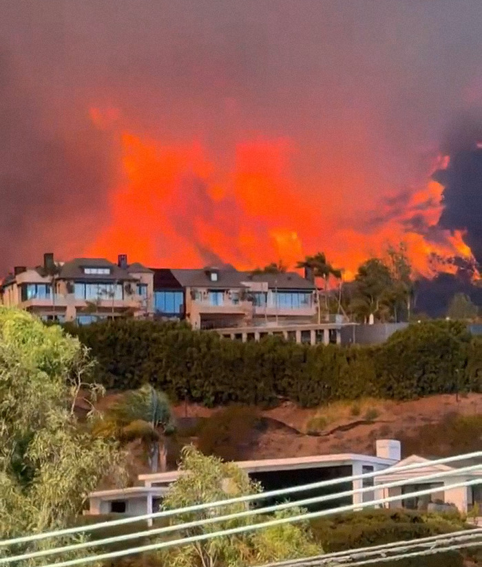LA wildfires blaze behind homes.