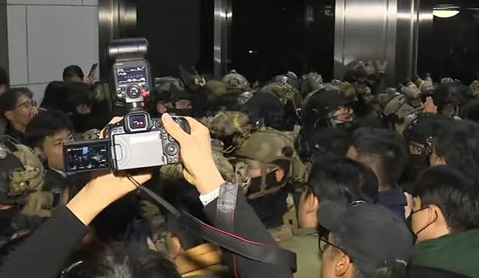 Parliament rejects South Korea's martial law, crowd of people and media cameras capturing the scene.