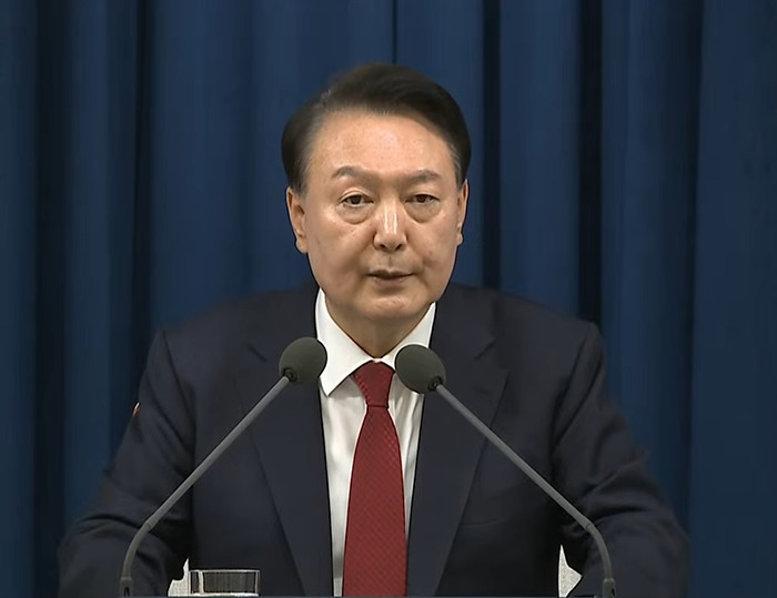 South Korea's president at a podium, addressing martial law rejection by parliament.