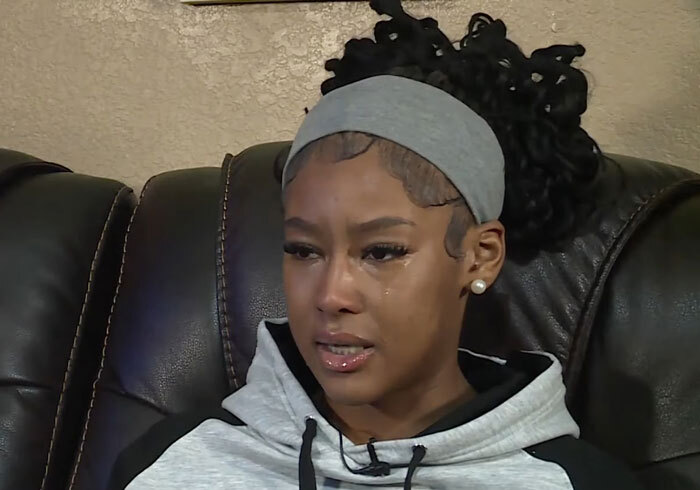 Woman in a gray headband and hoodie tearfully discussing a viral baton incident.
