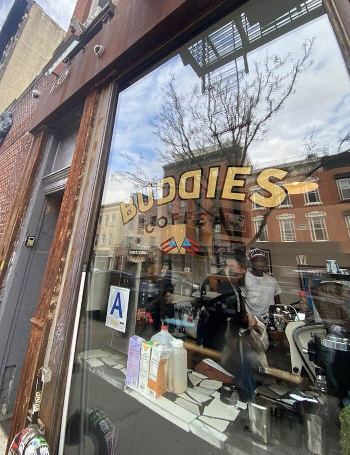 NYC cafe window with street reflections and people inside.