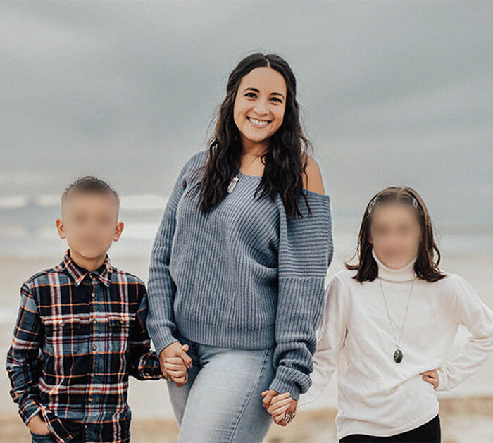 Woman holding hands with two children, smiling on a beach; keywords: Mormon family adoption.