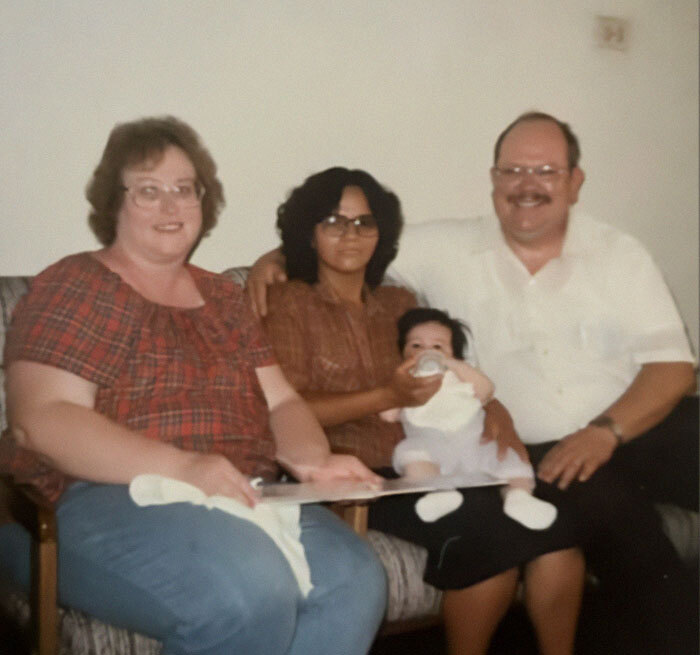 A family photo with a woman feeding a baby, related to a shady adoption story.
