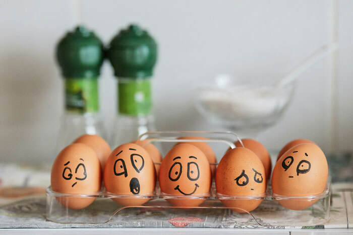 Carton of eggs with cartoon faces, reflecting humor about record-high egg prices in the US.