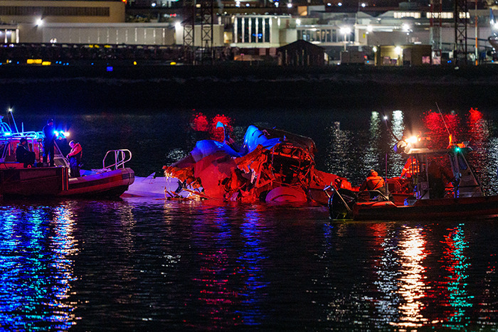 Rescue boats at night near wreckage of American Airlines plane crash in DC waters.