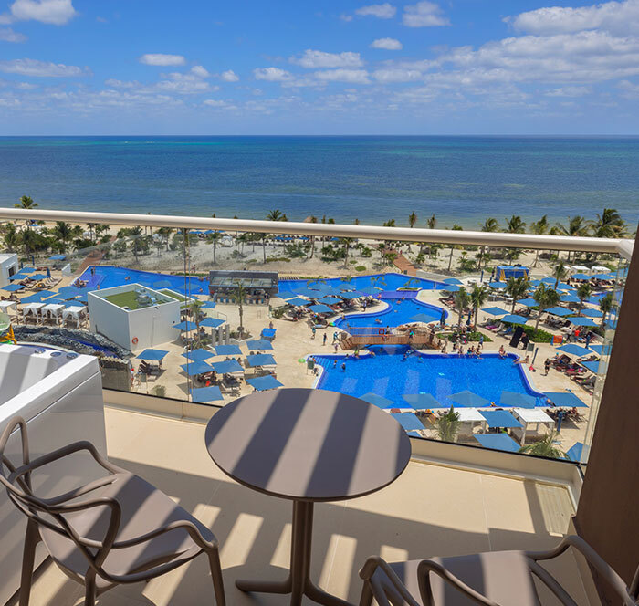 Ocean view from a Cancun resort balcony overlooking pools, highlighting family vacation atmosphere.