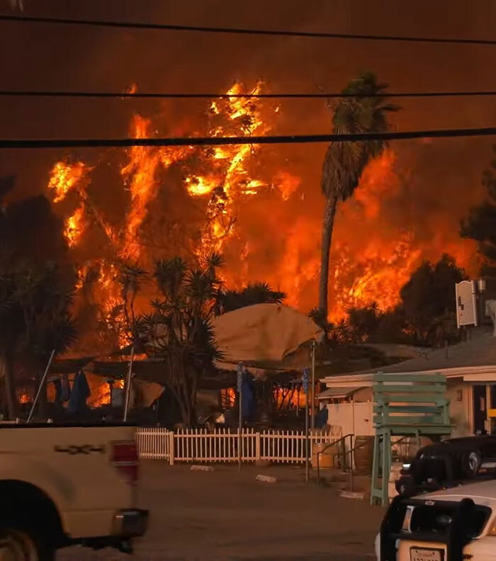 La Palisades fire raging near homes, sparking conspiracy theories.