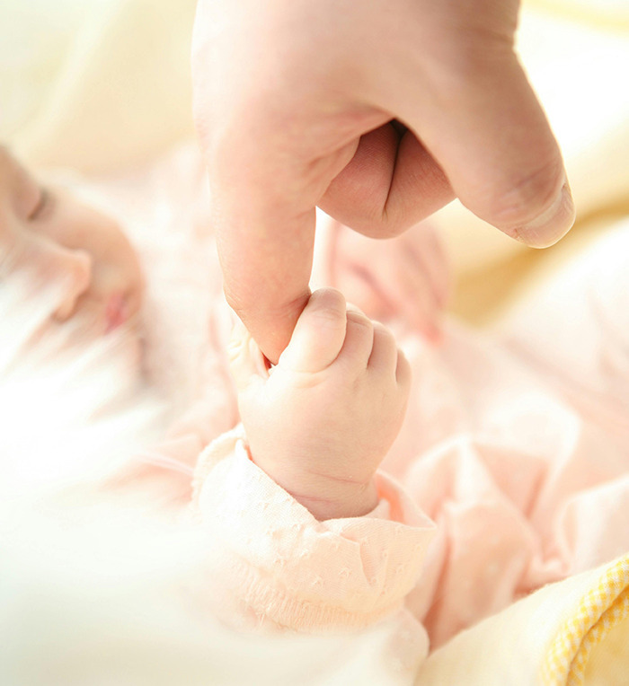 Baby holding an adult&rsquo;s finger, representing Generation Beta connection.