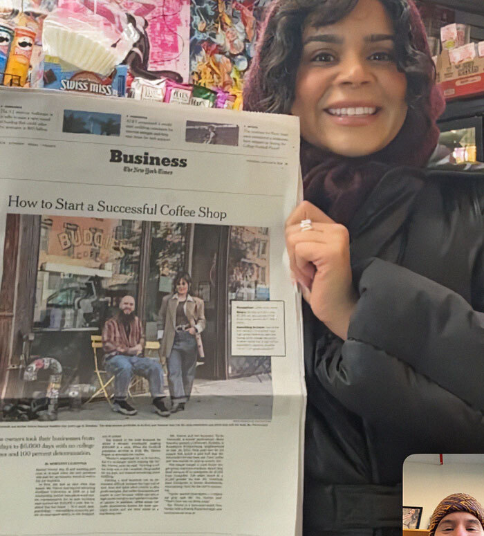 Smiling woman holds newspaper featuring NYC cafe success story article.