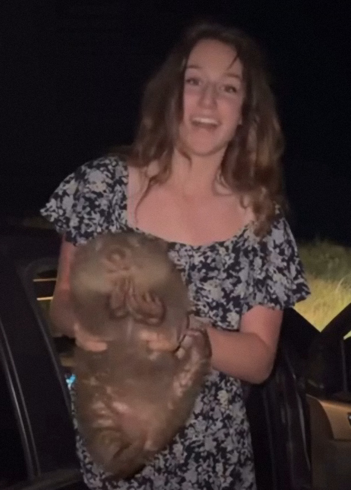 Woman holding baby wombat at night, generating calls for the tourist's deportation.