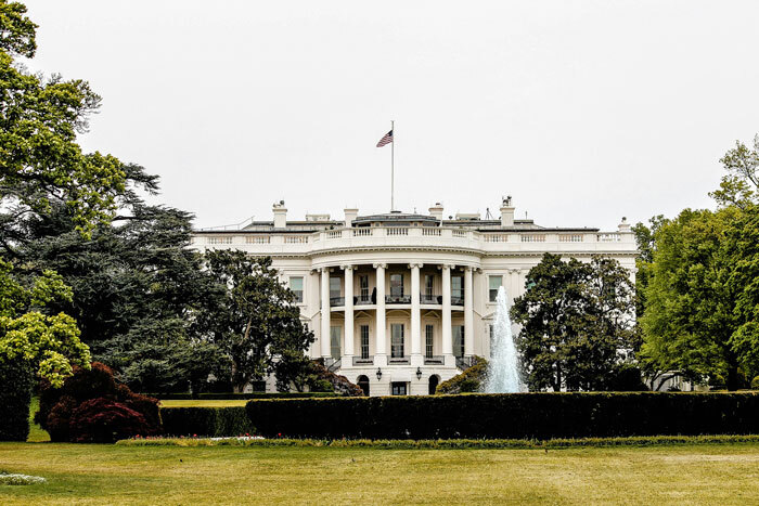 White House exterior, lush garden, central fountain; related to the Black Hawk conspiracy and DC plane crash drill.