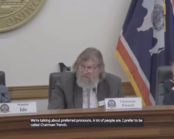 Sen. Tim French seated at meeting with a state flag in the background.