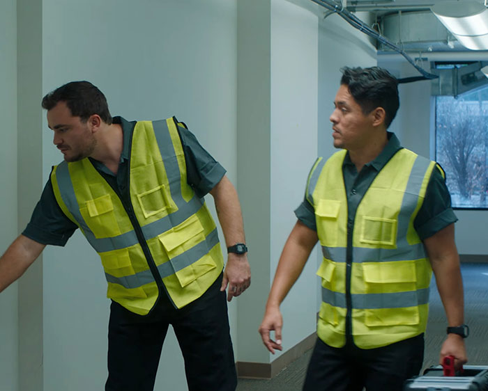 Workers in yellow vests in a hallway, illustrating impact of Republicans on working class.
