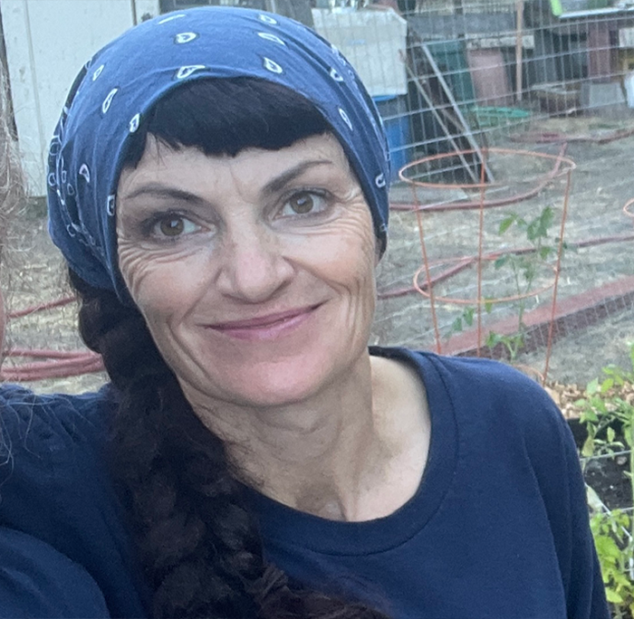 Irish woman living legally in the U.S. for 30 years wearing blue bandana and shirt outdoors in a garden setting