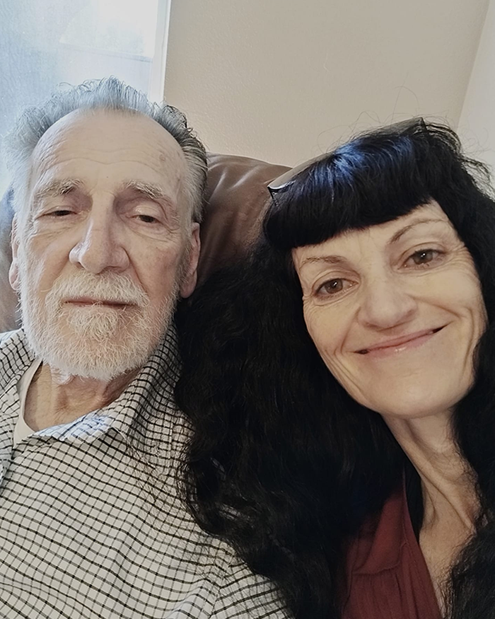 Irish woman living legally in the U.S. for 30 years smiling next to an elderly man in a home setting.