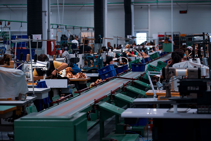 Factory workers busy at machines, illustrating direct buying strategy to avoid tariffs.