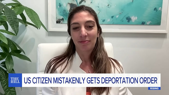 US-born doctor facing deportation order, seated indoors wearing a white jacket, with artwork and plants in the background.