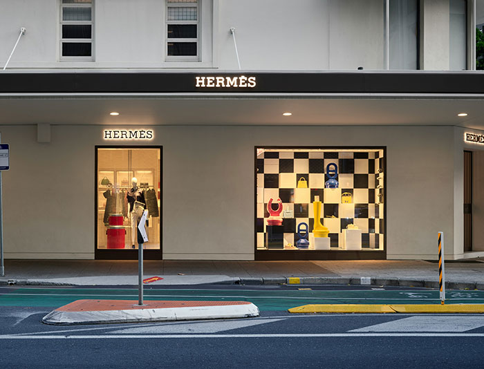 Herm&egrave;s storefront with vibrant window display, showcasing direct-buy fashion choices, avoiding tariffs.