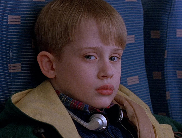 Young boy with headphones in a plane seat, from a scene in "Home Alone 2".