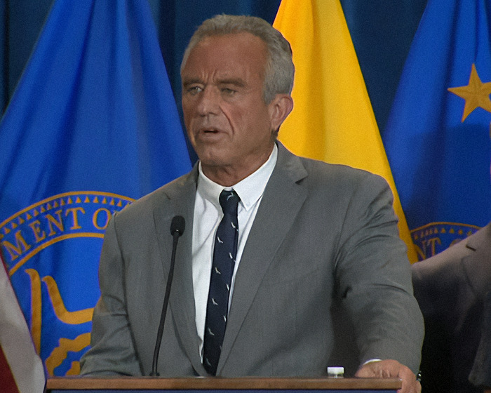Man in a suit speaking at a podium, addressing concerns about an autism registry plan.