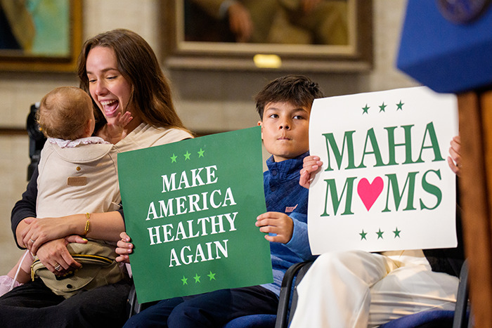 A woman and child hold signs about health during a discussion on autism registry and private medical records.