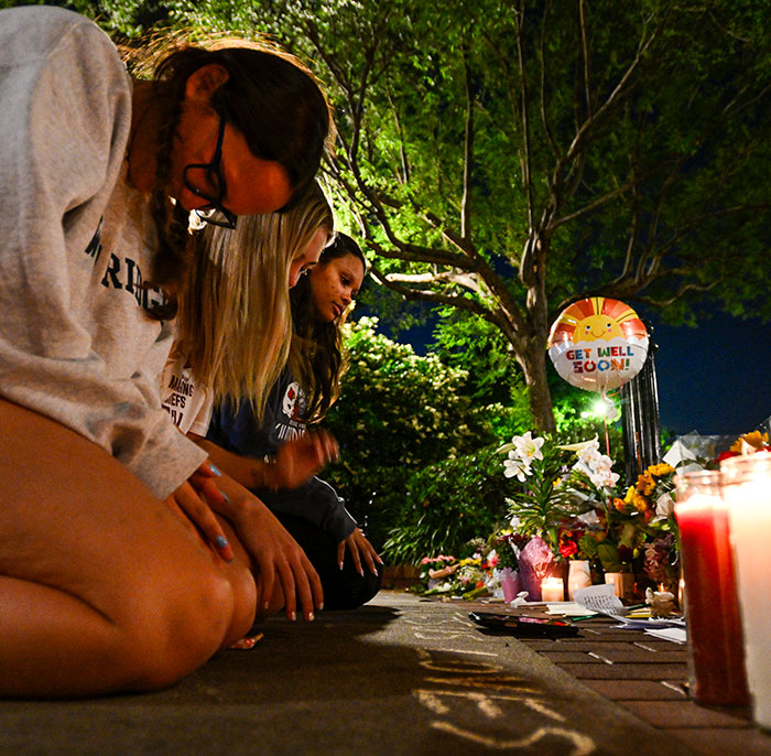 Mourners gather at a candlelit memorial, honoring victims of the FSU shooter rampage, amidst flowers and heartfelt messages.