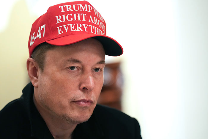 Man wearing a red cap, contemplating Tesla earnings.