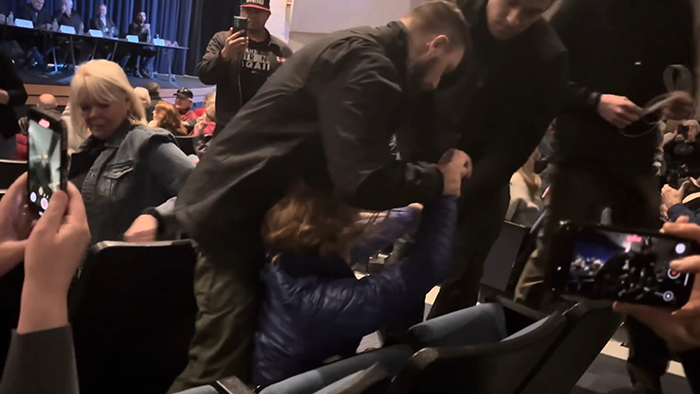A woman is being forcibly removed from a seat at a Republican town hall.