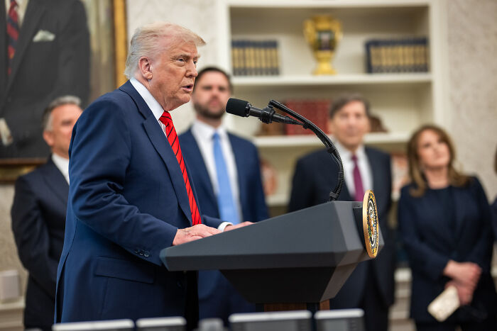 Donald Trump speaking at a podium in a formal setting as part of effort to rename Gulf and alter US maps.