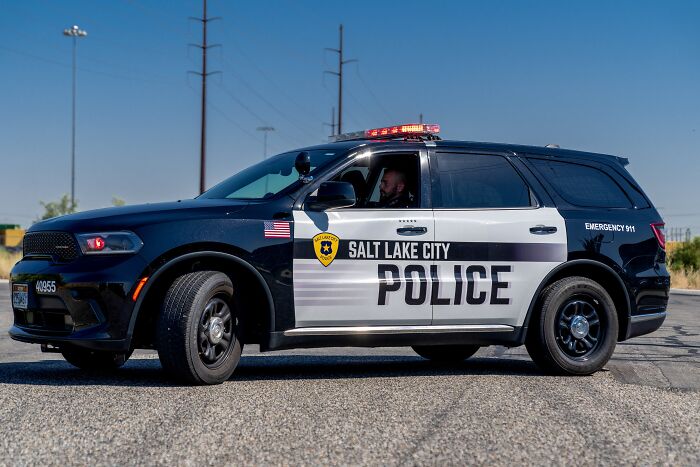 Salt Lake City police vehicle parked on a road during investigation of alleged hostage situation involving cartel protection.