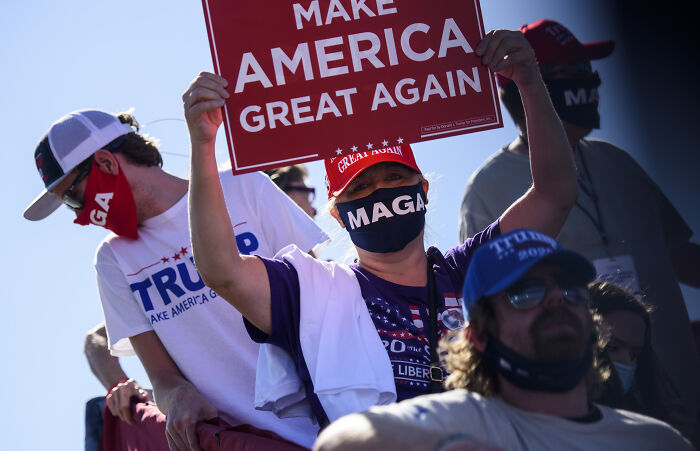 Supporters wearing MAGA gear and holding Make America Great Again signs at a political rally discussing Pope Leo XIV&rsquo;s agenda.