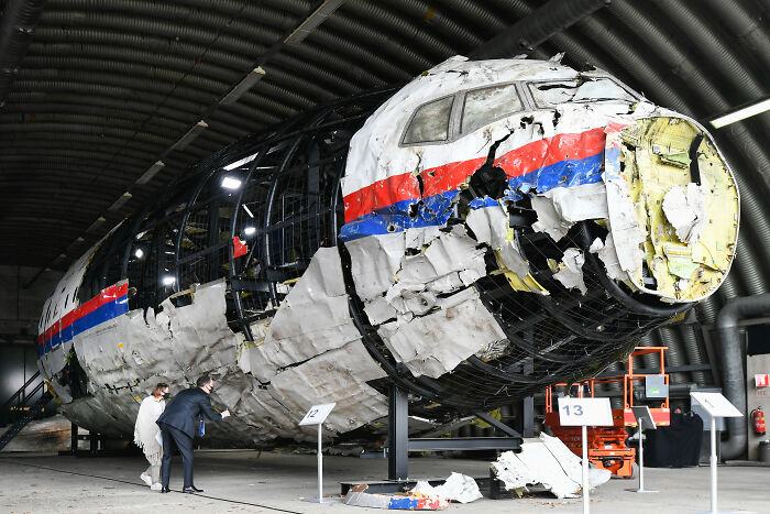 Wreckage of MH17 airplane with damaged fuselage inside hangar, related to Russia found liable by UN aviation agency.