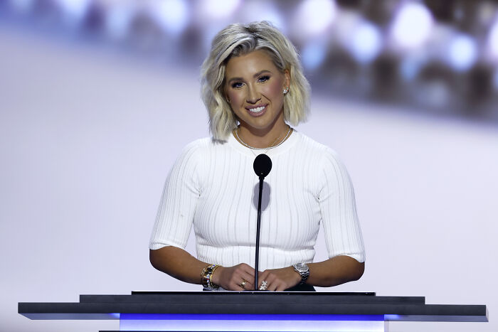 Savannah Chrisley speaking at a podium, reacting to Trump pardoning reality TV parents convicted of bank fraud.