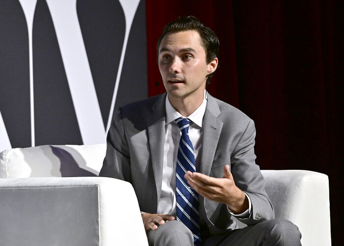 Man in gray suit and striped tie speaking during a formal event about DNC committee votes and David Hogg&rsquo;s election.