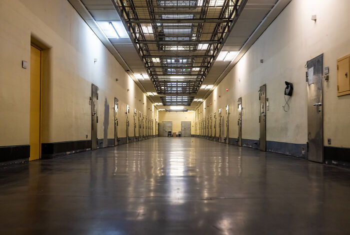 Empty corridor in a detention facility with metal doors on both sides, reflecting the harsh reality of orphanage abuse victims.