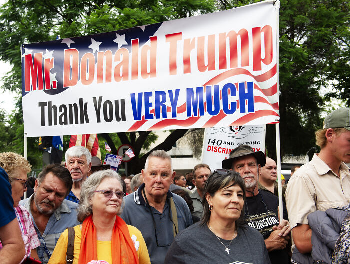 Group of white South Africans holding a banner supporting Donald Trump during departure for refugee status in the U.S.