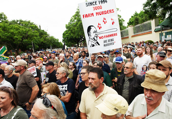 Large crowd of white South Africans protesting farm murders before departing for the U.S. under refugee status.