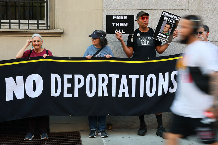 Protesters holding no deportations banner and signs against deporting Asian migrants during a public demonstration.