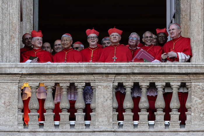 Group of cardinals in red robes on a balcony, highlighting clues to Pope Leo XIV&rsquo;s agenda and MAGA reaction.