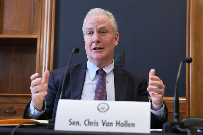 Senator Chris Van Hollen speaking during a meeting, discussing deportees and related political issues.