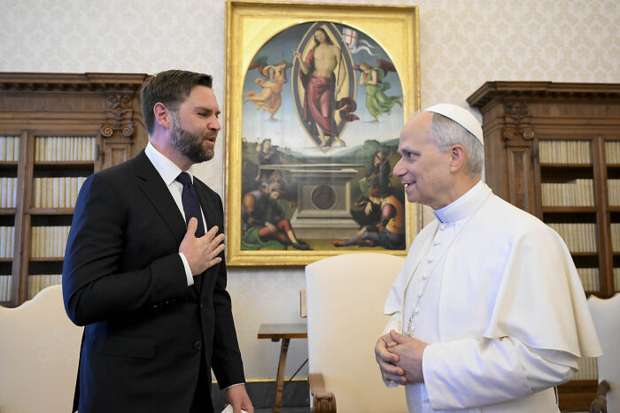JD Vance speaking with Pope Leo in a formal room with religious artwork during the inaugural Mass in Rome.