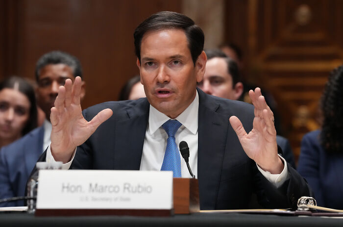 Senator Marco Rubio speaking at a hearing, discussing deportees and related political issues in a formal setting.