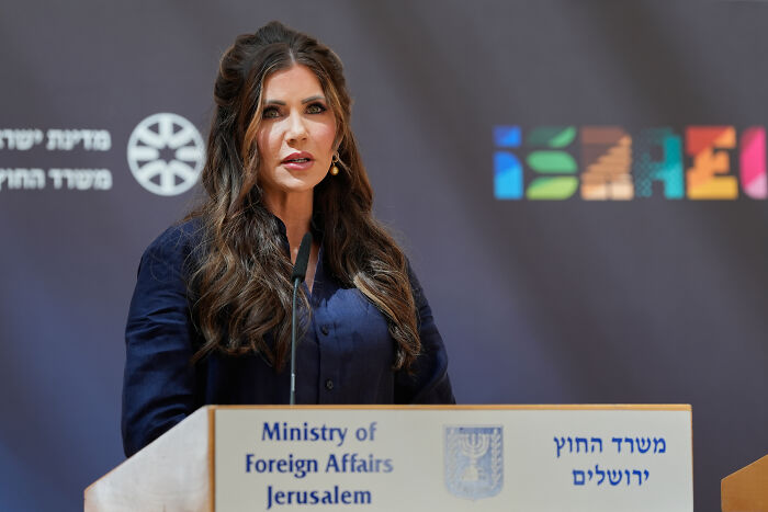 Woman speaking at Ministry of Foreign Affairs podium in Jerusalem amid student visa freeze and social media profile checks.
