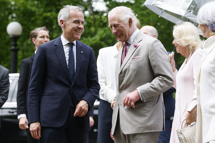 Two men in suits smiling and conversing outdoors, illustrating discussion on bold defense deal with Canada and US integration.