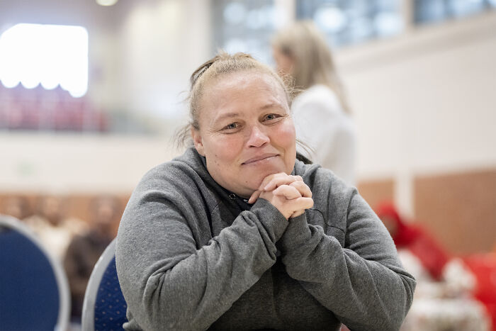 Woman in gray hoodie sitting with hands clasped, relating to mother jailed for life after selling daughter case.